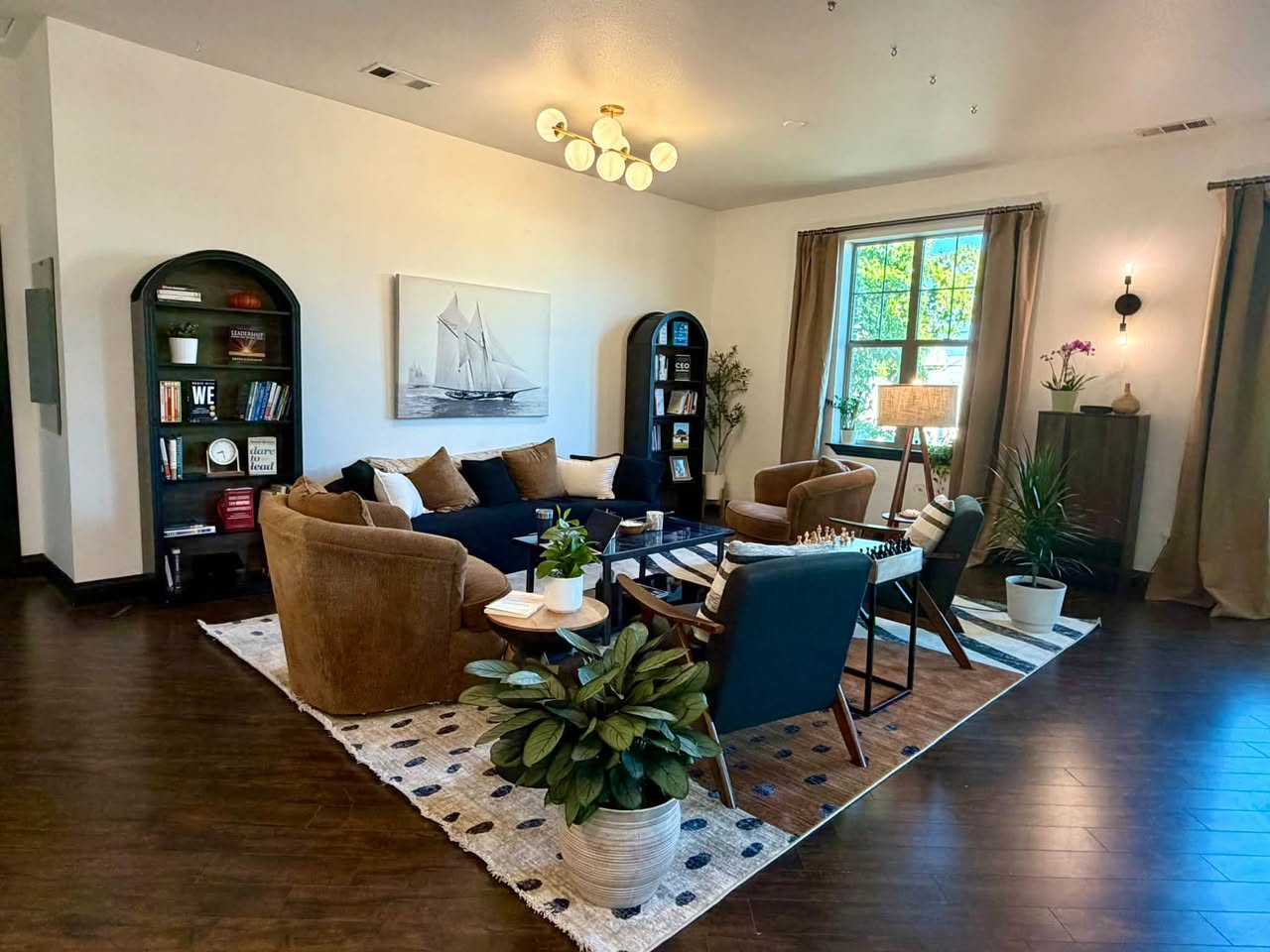Lounge area with a sectional sofa, armchairs, a coffee table, bookshelves, and large windows